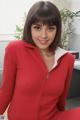 A woman in a red jacket sitting on a desk.