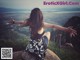 A woman sitting on top of a mountain with her arms outstretched.
