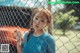 A young girl standing behind a chain link fence.