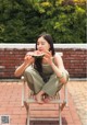 A woman sitting on a chair eating a slice of watermelon.