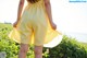 A woman in a yellow dress standing in a field.