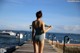 A woman in a bathing suit standing on a pier by the water.