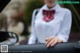 A woman in a white shirt and red bow tie sitting in a car.