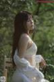 A woman in a white dress sitting on a wooden chair.