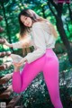 A woman in pink leggings and a white sweatshirt is posing for a picture.