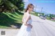 A woman in a white dress standing on the side of a road.