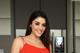 A woman in a red dress standing in front of a refrigerator.