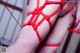 A close up of a woman's legs tied up with red string.